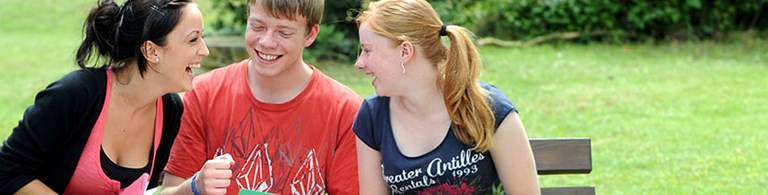 Zwei Frauen und ein junger Mann auf einer Bank
